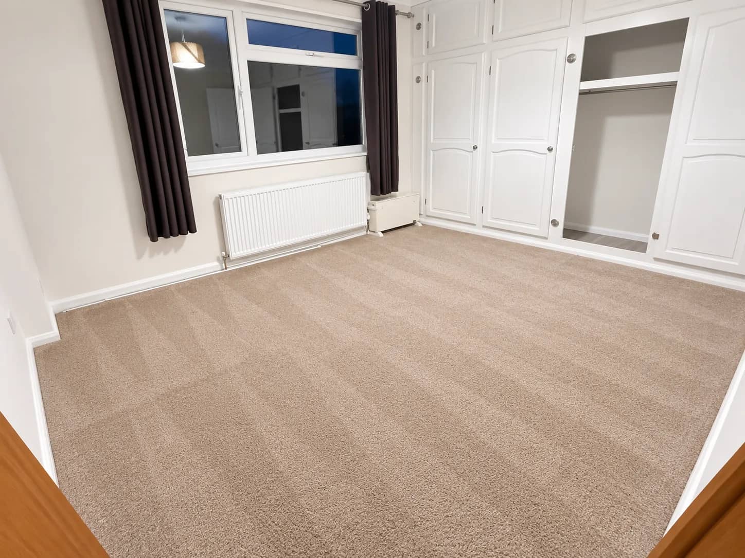 A bedroom carpet left clean beside fitted wardrobes.