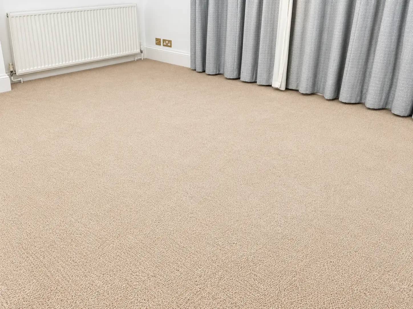 A beige carpet cleaned in an empty room before new occupants move in.