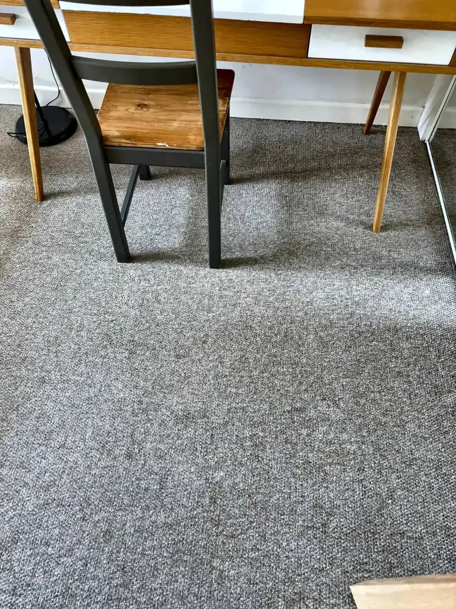 Grey contract carpet cleaned around desks and chair legs.