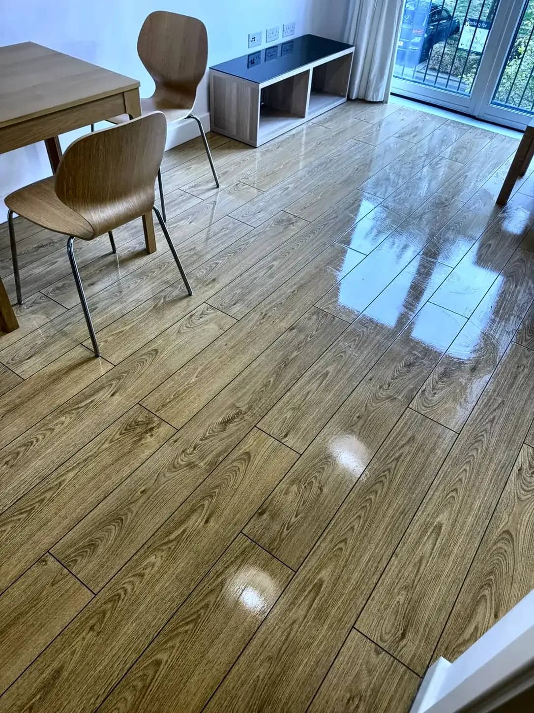 A wood-effect floor polished through a dining area after a hard floor clean.