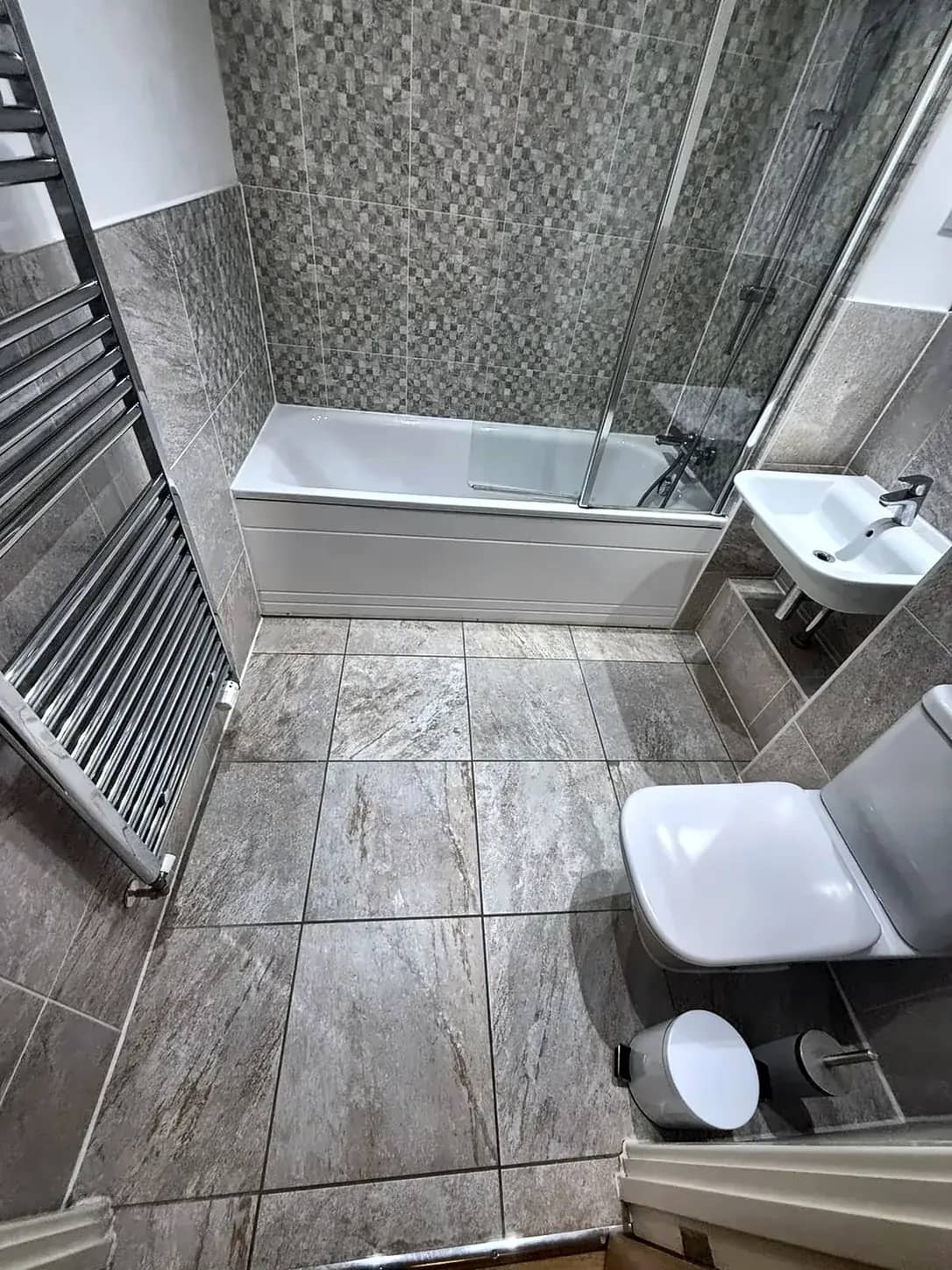 A tiled bathroom with the bath, basin and toilet left clean after a deep clean.